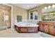 Bathroom features a soaking tub, a window, a walk-in shower, and double vanities with wood cabinets at 791 Elk Rest Rd, Evergreen, CO 80439