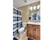 This bathroom offers a toilet, single sink vanity with wooden cabinets, and a shower with a striped curtain at 791 Elk Rest Rd, Evergreen, CO 80439