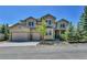 Well-maintained home showcasing tan and stone exterior, a well manicured front yard, and three car garage at 791 Elk Rest Rd, Evergreen, CO 80439