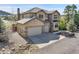 Suburban home with stone accents, neutral siding, three-car garage, and landscaped yard with beautiful rock features at 791 Elk Rest Rd, Evergreen, CO 80439