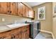 This laundry room features wooden cabinets, a white sink, and a modern gray washer and dryer at 791 Elk Rest Rd, Evergreen, CO 80439
