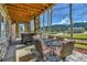 Covered stone patio area includes a hot tub, outdoor dining set, and serene mountain view with blue sky at 791 Elk Rest Rd, Evergreen, CO 80439