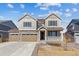 Charming two-story home featuring a three-car garage, stone accents, and a welcoming front porch at 25041 E 38Th Ave, Aurora, CO 80019