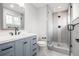 Bathroom featuring modern fixtures, a tiled shower with glass door, grey vanity, and large mirror at 3999 W Chenango Ave, Littleton, CO 80123