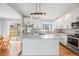 Bright kitchen with white cabinets, stainless appliances, island with granite countertops, and hardwood floors at 3999 W Chenango Ave, Littleton, CO 80123