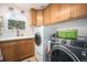 A bright laundry room with wooden cabinets, a sink, and modern washer and dryer units at 12051 E Lake Cir, Greenwood Village, CO 80111
