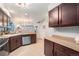 Open concept kitchen with dark wood cabinets and stainless steel appliances overlooks living area with staircase at 5252 W 68Th Ave, Arvada, CO 80003