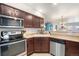 Well-lit kitchen featuring stainless steel appliances, including microwave, range, and dishwasher, and dark wooden cabinetry at 5252 W 68Th Ave, Arvada, CO 80003