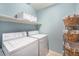 Functional laundry room features a washer, dryer, storage shelves, and laundry baskets at 5252 W 68Th Ave, Arvada, CO 80003