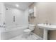 Bright bathroom featuring a tiled tub with shower, pedestal sink, and neutral color palette at 1631 N Emerson St # 207, Denver, CO 80218