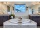 A luxurious bathroom featuring a soaking tub with dual sinks and mirrors above dark cabinetry at 7485 S Jackson Gap Way, Aurora, CO 80016