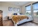 A modern bedroom featuring a comfy bed, a nightstand, and bright natural light from a nearby window at 7485 S Jackson Gap Way, Aurora, CO 80016