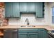 Modern kitchen featuring sleek, teal cabinets, subway tile backsplash, and stainless-steel appliances at 1560 Clinton St, Aurora, CO 80010