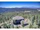 Gorgeous home surrounded by lush forest and distant mountains under a blue sky at 28154 Belle Mont Trl, Conifer, CO 80433