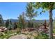 Scenic backyard featuring a tiered water feature, lush landscaping, and mountain views at 28154 Belle Mont Trl, Conifer, CO 80433