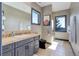 Bathroom with travertine countertops, a black toilet, a large mirror, and natural light at 28154 Belle Mont Trl, Conifer, CO 80433