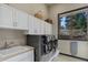 Bright laundry room features white cabinets, front-loading washer and dryer, and a view at 28154 Belle Mont Trl, Conifer, CO 80433
