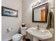 Cozy powder room features a pedestal sink, framed mirror, and mountain-themed artwork at 278 Snowshoe Cir, Breckenridge, CO 80424