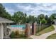 A community pool enclosed by a black metal fence with picnic tables and lounge chairs, and a brick entryway sign at 4821 W 102Nd Ave, Westminster, CO 80031