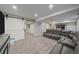 Basement living room features a large sectional sofa, sliding barn door, and access to additional finished spaces at 23298 Barnsley Ln, Parker, CO 80138