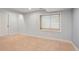 Neutral basement room with soft carpet, natural light from the window, and a paneled door at 5740 S Tempe Ct, Aurora, CO 80015