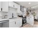 Modern white kitchen with stainless steel appliances and black hardware accents at 4910 Alcott St, Denver, CO 80221