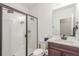 Bright bathroom features a glass-enclosed shower, white tiled walls, and a vanity with a dark wood cabinet at 22773 E Narrowleaf Cir, Aurora, CO 80016
