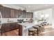 Bright kitchen featuring dark wood cabinetry, white countertops, a large island, and barstool seating at 22773 E Narrowleaf Cir, Aurora, CO 80016