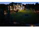 Expansive backyard at dusk, featuring a large lawn, manicured landscaping, and an elegant, well-lit home at 8717 Ridgepoint Dr, Castle Pines, CO 80108
