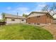 A brick home's backyard featuring a green lawn, rock garden, and small concrete patio space at 1327 E 108Th Pl, Northglenn, CO 80233