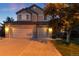 Two-story home featuring brick facade and a three-car garage, set against a twilight sky at 15565 Flowerhill Cir, Parker, CO 80134