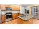 Open kitchen features wood cabinets, granite counters, stainless steel appliances, and a kitchen island with a double sink at 15565 Flowerhill Cir, Parker, CO 80134