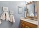 Bright bathroom with a wooden vanity, decorative mirrors, and blue wall paint at 1799 S Lee St # B, Lakewood, CO 80232