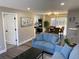 Cozy living room featuring a blue sofa, dark wood floors, and access to the kitchen and dining area at 1263 N Willow St, Denver, CO 80220