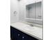 Bathroom vanity with a white sink, speckled countertops, a mirror, and navy blue cabinets at 1293 S Monaco Pkwy, Denver, CO 80224