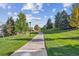 Serene community walking path lined with lush green grass and trees, perfect for an afternoon stroll at 10685 Cherrybrook Cir, Highlands Ranch, CO 80126