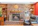 Close-up view of a cozy brick fireplace with built-in shelves, and hardwood flooring at 12752 W Dakota Ave, Lakewood, CO 80228