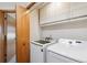Functional laundry room with a washer, dryer, storage cabinets, and a door at 12752 W Dakota Ave, Lakewood, CO 80228