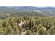 Stunning aerial view of the home nestled among towering pine trees with mountain views at 4992 White House Trl, Evergreen, CO 80439