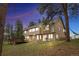 Charming two-story home with a wooden deck, beautiful lawn, and mature trees at dusk at 4992 White House Trl, Evergreen, CO 80439