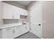 Functional laundry room with white cabinets, quartz countertop, sink, and neutral-toned flooring at 8014 Trinity Peak Ln, Castle Rock, CO 80108