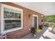 Charming brick home featuring a cozy front porch with gray plank flooring and potted plants at 3375 N Willow St, Denver, CO 80238