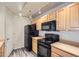 Well-lit kitchen featuring sleek black appliances, ample wood cabinets, and modern track lighting at 5255 Memphis St # 224, Denver, CO 80239