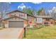 Quaint two-story home with gray siding, a red front door, an attached garage, and landscaped front yard at 7148 S Dahlia Ct, Centennial, CO 80122