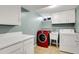 Laundry room with a red washing machine, white dryer, and storage cabinets at 7148 S Dahlia Ct, Centennial, CO 80122
