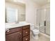 Bathroom featuring wood vanity, a white countertop, toilet, shower with glass door, and neutral colored tile flooring at 10154 Belvedere Loop, Lone Tree, CO 80124