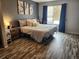 Cozy bedroom with wood-look flooring, stylish gray walls, and decorative wall art above the bed at 14344 E Hawaii Cir # B, Aurora, CO 80012