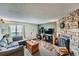 Welcoming living room with a stone fireplace, wood floors, a comfortable gray sofa, and ample natural light at 14344 E Hawaii Cir # B, Aurora, CO 80012