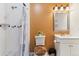 Well-lit bathroom features tile shower, toilet, and vanity with a sink, and an orange painted wall at 625 S Xenon Ct, Lakewood, CO 80228