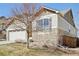 Side view of home featuring a two-car garage, stone accents, and low maintenance yard at 24437 E Powers Ave, Aurora, CO 80016